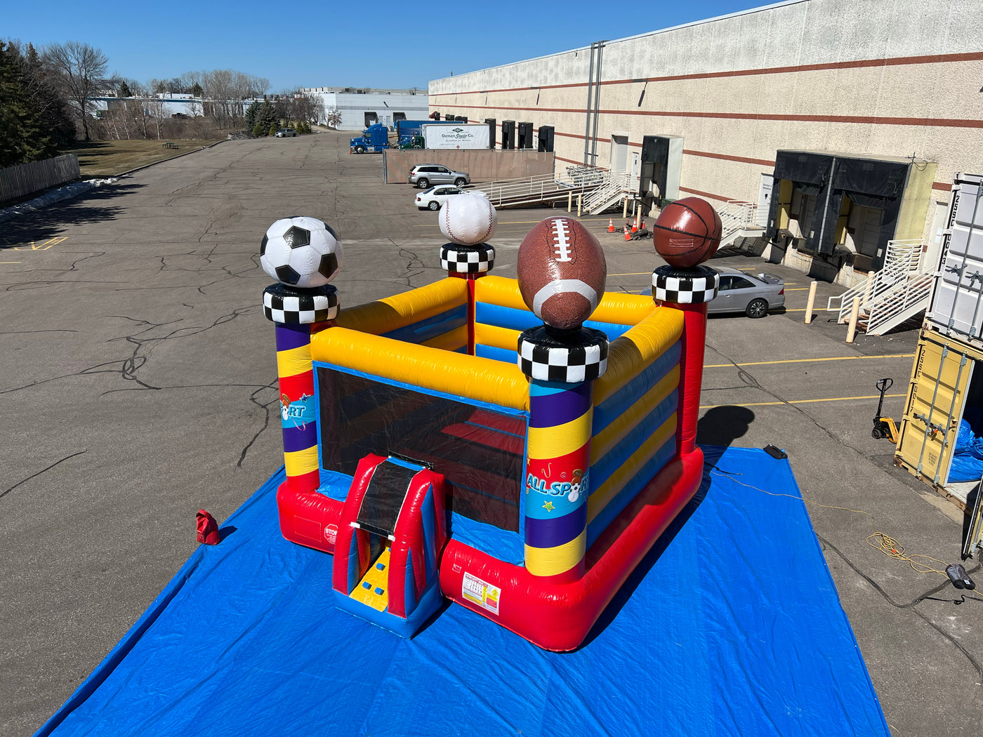 All Sport Bouncer Inflatable with sports ball decorations setup outside on large blue tarp