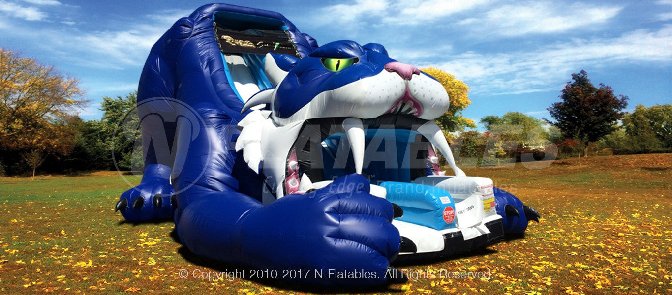 Giant blue sabretooth tiger inflatable slide set up in a park. 