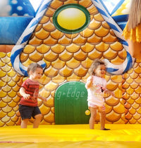 Two toddler kids jumping inside the Candy Playland™ play area with a gingerbread house background. 