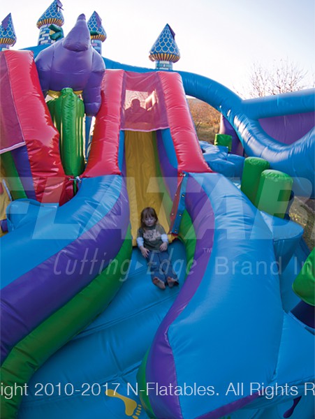 A kid sliding down the Castle Fun Centre™ inflatable playground. 