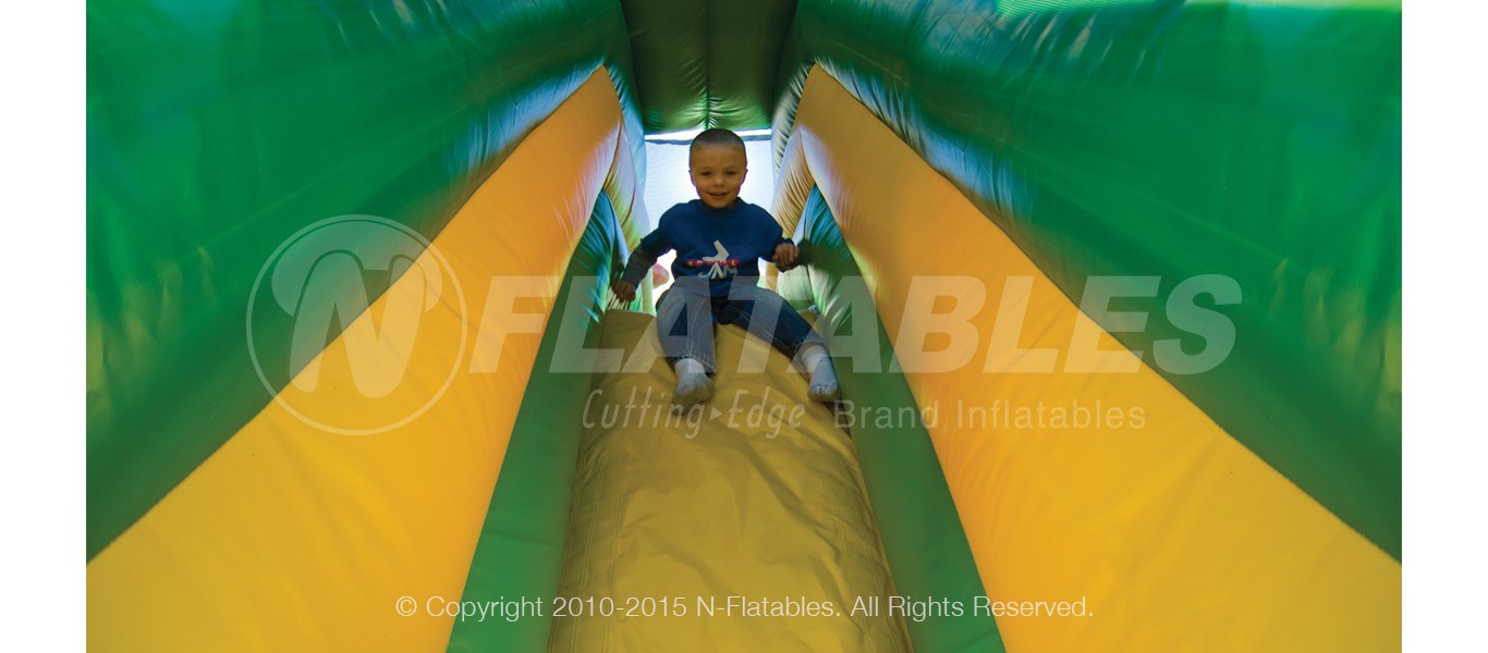 Boy sliding down the Rainforest Fun Center inflatable playground.