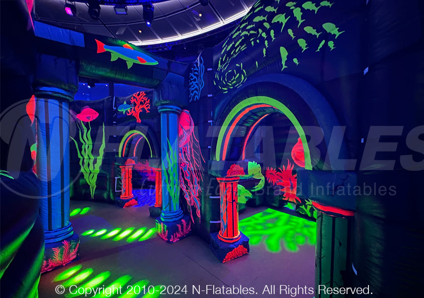 The inside of a custom inflatable laser tag maze with blacklights on revealing colorful  ocean-themed digital printing. 