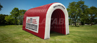 A red and white inflatable tunnel for sports players set up in a park. 