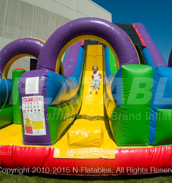 A kid sliding down the Wacky Slide Combo™ inflatable playground. 